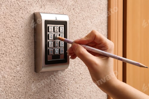 Preview: Woman using pencil to enter code on electronic lock's keypad indoors, closeup