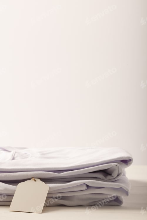 Preview: Stack of white t shirts with tag and copy space on white background