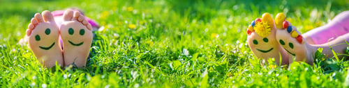 Preview: Child feet on the grass drawing a smile. Selective focus.