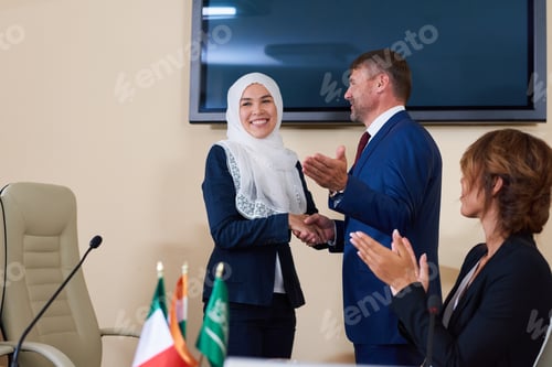 Preview: Young confident businessman shaking hand of successful female speaker