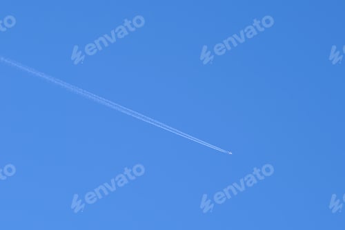 Preview: Distant passenger jet plane flying on high altitude on clear blue sky leaving white smoke