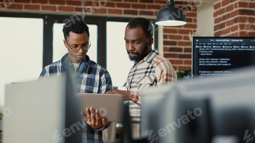 Preview: Coders talking about algorithms holding laptop pointing at sorce code on screen