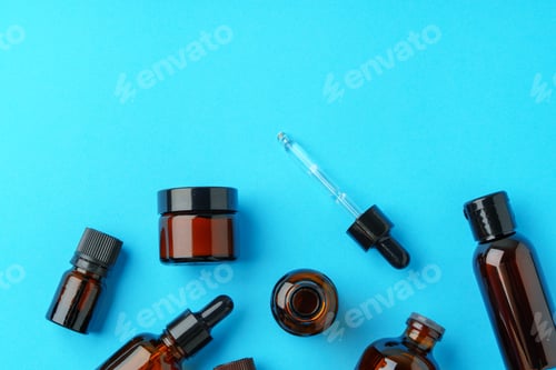 Preview: Collection of Amber Glass Bottles and Jars Displayed on Bright Blue Background