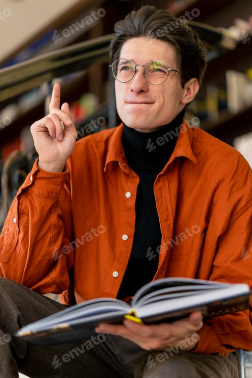 Preview: guy sits on the stairs and reads a book enthusiastically shocked by the plot of the events of story