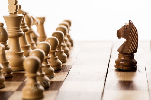 Preview: Selective focus of brown knight against chess pieces on chessboard isolated on white
