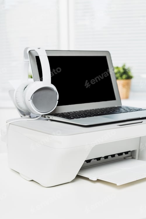 Preview: Home office setup with laptop, printer, and headphones in a bright workspace