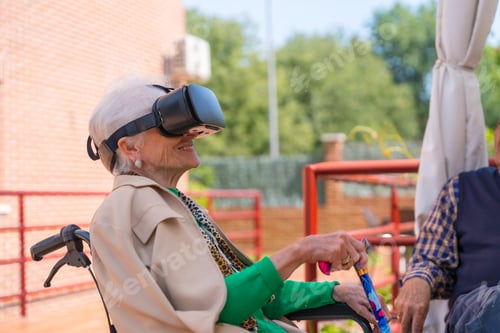 Preview: An elderly woman with the nurse looking through virtual reality glasses in the garden of a nursing