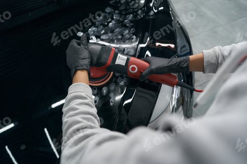 Car Detailer Polishing Black Car with Power Tool