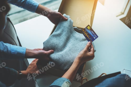 Preview: Women holding and using credit card for online shopping while opening a postal parcel box