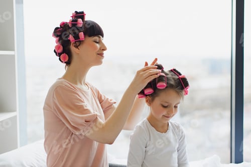 Preview: Woman Putting Hair Curlers in a Child's Hair