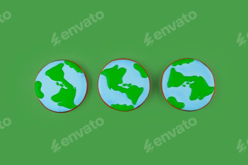 Preview: Earth Day concept. Three cookies in shape of Earth on green backdrop.