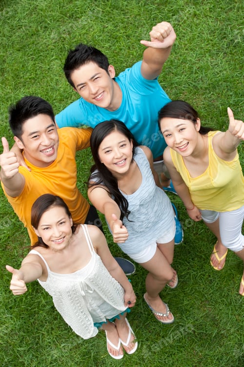 Preview: Young people doing thumbs-up on meadow