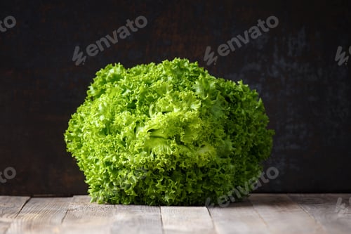 Preview: A large bunch of fresh lettuce leaves on a wooden table and a dark background.