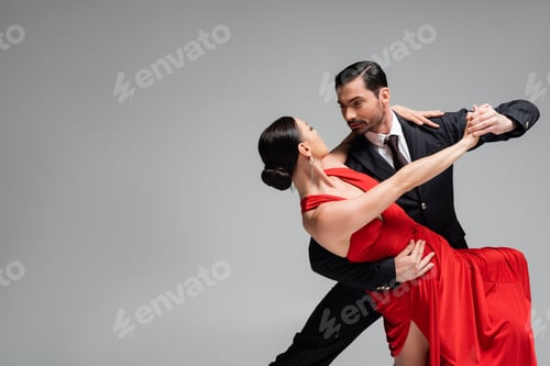 Preview: Elegant man in suit dancing tango with partner isolated on grey
