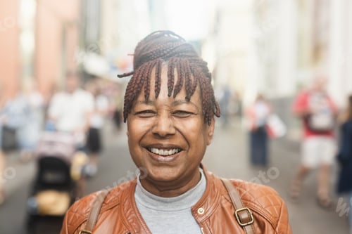 Preview: Happy senior african american woman smiling in front of camera with city in background