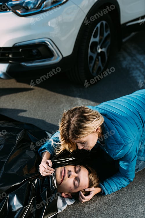 Preview: high angle view of young woman crying about dead man on road after traffic collision