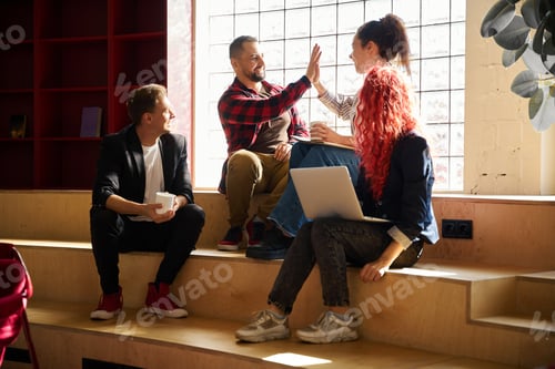 Preview: Friends looking at smiling man and woman interchanging high five