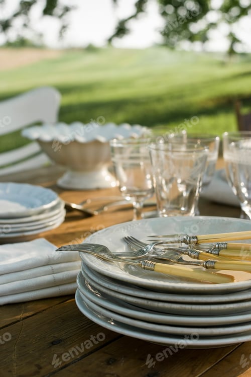 Preview: A table laid in a garden, with white china crockery and cutlery. Summer.