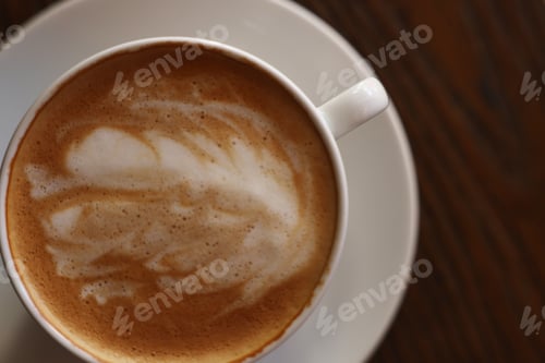 Preview: Cup of aromatic coffee with foam on wooden table, top view