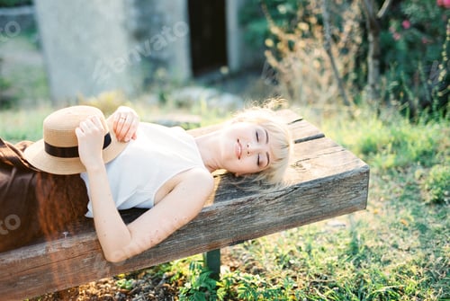 Preview: Woman with closed eyes lies on a wooden bench