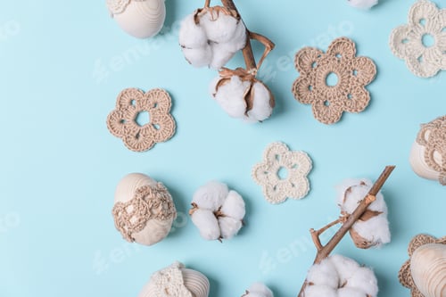 Preview: Craft eggs, knitted and cotton flowers on blue background. Top view. Copy space