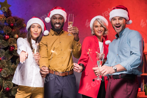 Preview: multiethnic businesspeople holding christmas sparklers and glasses of champagne at new year