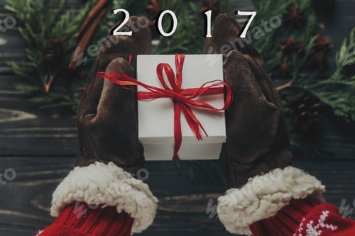Preview: Hands in vintage gloves holding christmas present with red bow
