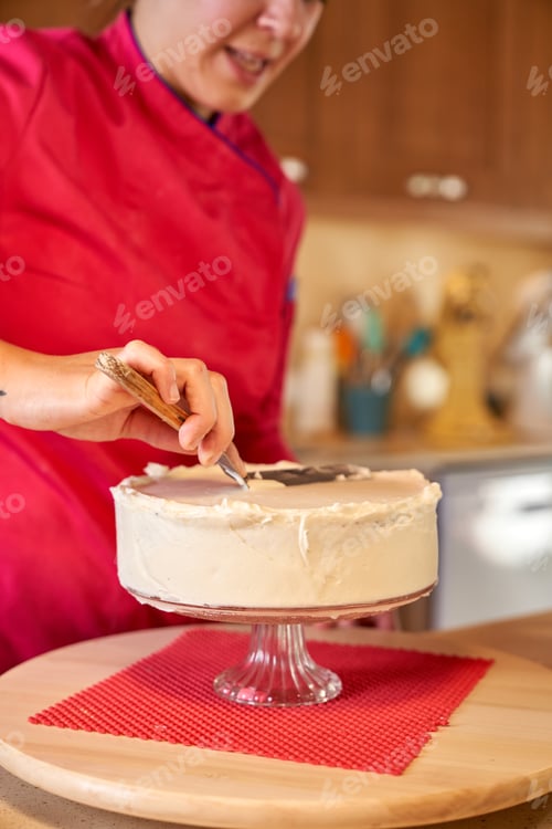 Preview: Woman in professional clothes making cake at home