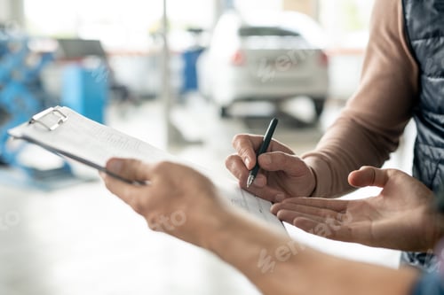 Preview: Hand of technician of car repair service explaining man where to put signature