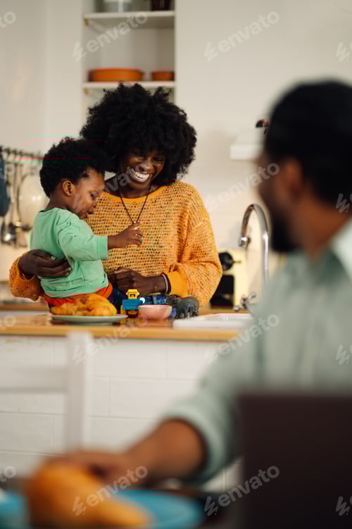 Preview: An african american mother and son are playing in the kitchen and preparing breakfast.