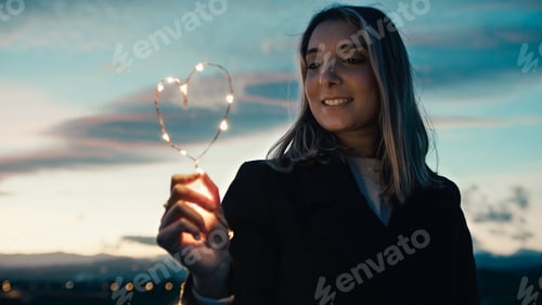 Preview: Woman Holds Heart Made of Lights at Sunset