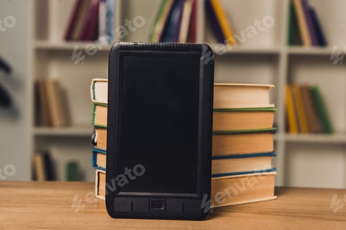 Preview: e-book with blank screen near paper books on table