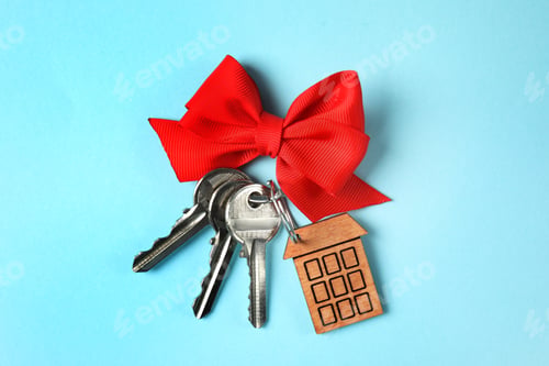 Preview: House keys with trinket and bow on color background, top view
