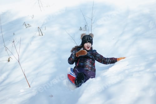 Preview: A cute ten years old teenage girl having fun on snow tube on a winter day. Wintertime, activity. N
