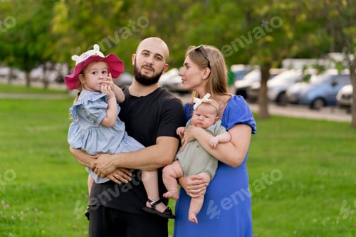 Visualização: uma mãe e um pai segurando crianças pequenas nas mãos e caminhando no parque ao ar livre