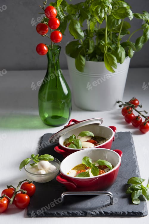 Preview: Italian caprese salad, baked cherry tomatoes, mozzarella and basil on a white table, still life