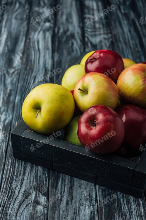 Preview: wooden box with ripe multicolored apples on grey table