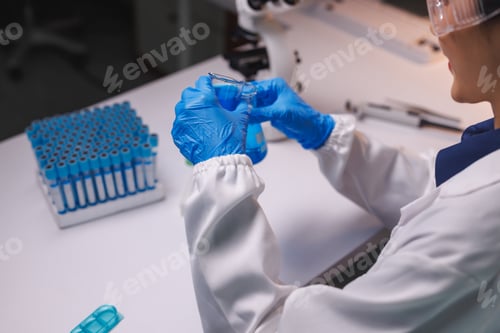 Preview: Scientist hands holding beaker with blue liquid in lab