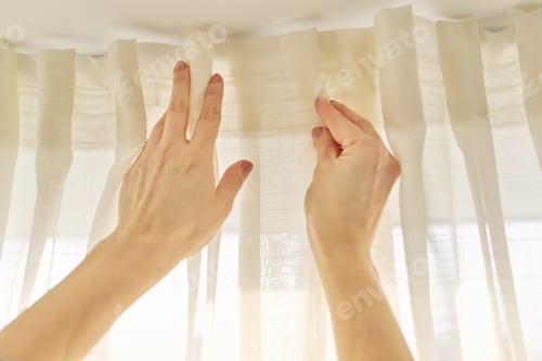 Preview: Close up of woman hands hanging curtain with metal hooks on ceiling ledge