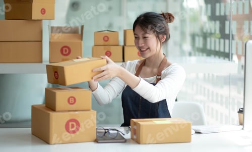 Preview: Smiling young Asian business owner woman prepare parcel box and standing check online orders of