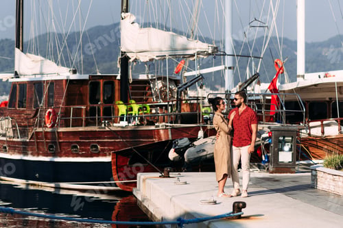 Preview: Man and woman near the yachts on the dock. Couple in love at the yacht