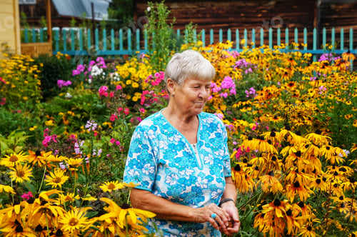 Preview: Senior Woman Smiling in a Colorful Flower Garden