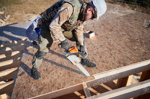 Preview: Carpenter using chainsaw for cutting OSB board for building wooden frame house.
