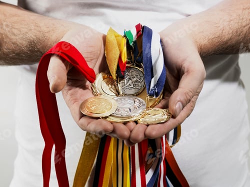 Preview: Mature man holding gold medals against white background