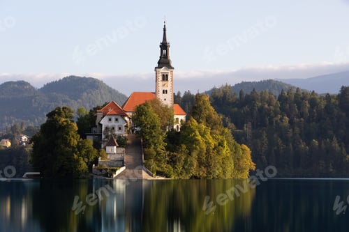 Preview: Church in Bled lake illuminated from side view at sunrise with clear