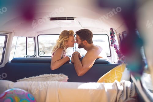 Preview: Side view of romantic Caucasian couple sitting in a camper van at beach