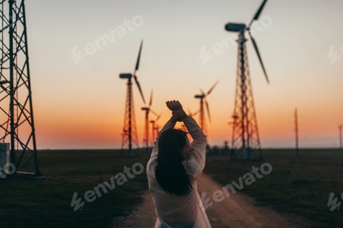 Preview: Woman enjoying windmills at golden hour landscape