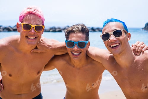 Preview: group of three friends having fun playing and enjoying together at the beach wearing sunglasses