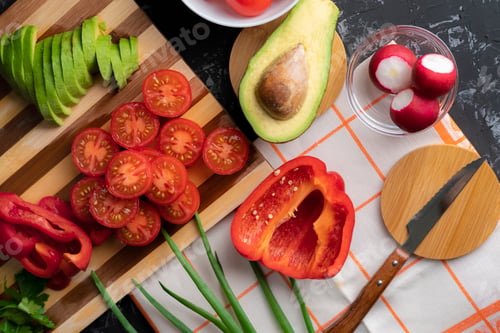 Preview: close up fresh organic flat lay sliced vegetables on the cutting board, tomato, avocado, peppers