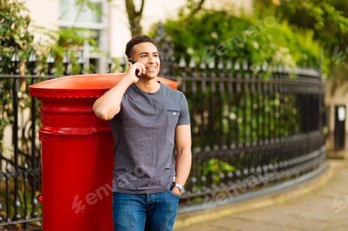 Preview: Man leaning against mailbox using smartphone